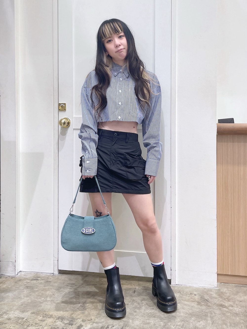 ブルー系のシャツ/ブラウス、ブラック系のスカート、ブルー系のショルダーバッグを着用したレディースの春コーディネートの2枚目の写真