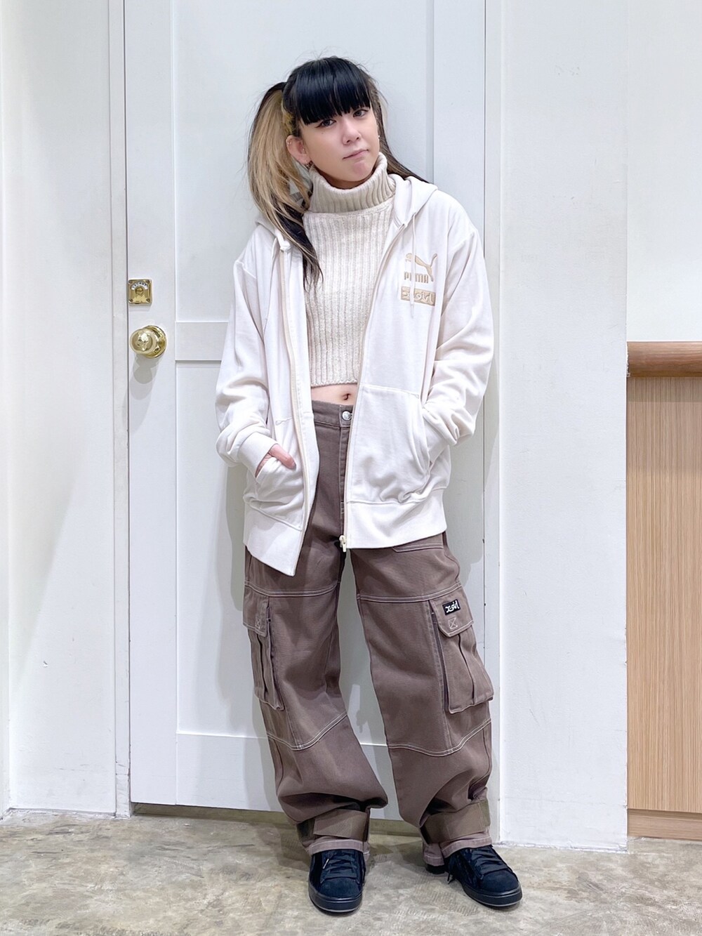 ベージュ系のパーカー、ホワイト系のニット/セーター、グリーン系のカーゴパンツを着用したレディースの秋コーディネートの2枚目の写真