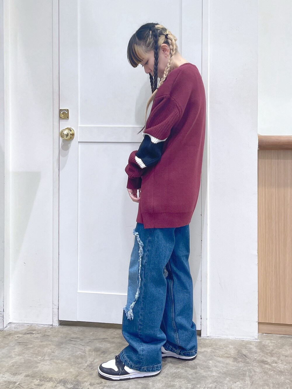 レッド系のニット/セーター、ブルー系のデニムパンツ、ホワイト系のマフラーを着用したレディースの冬コーディネートの3枚目の写真