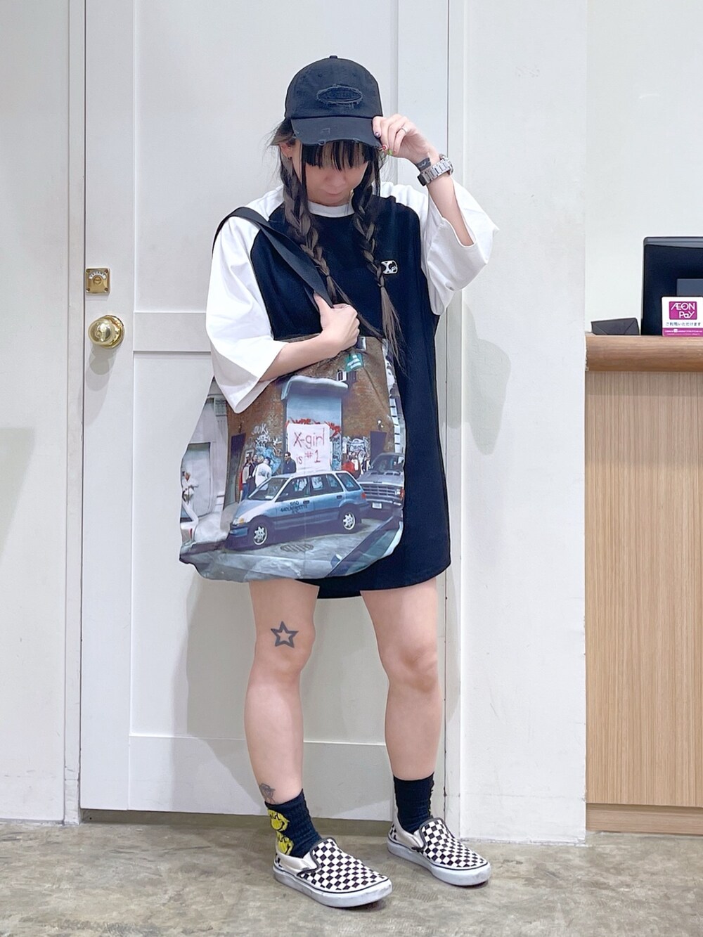 ブラック系のワンピース、その他のトートバッグ、グレー系のキャップを着用したレディースの夏コーディネートの2枚目の写真