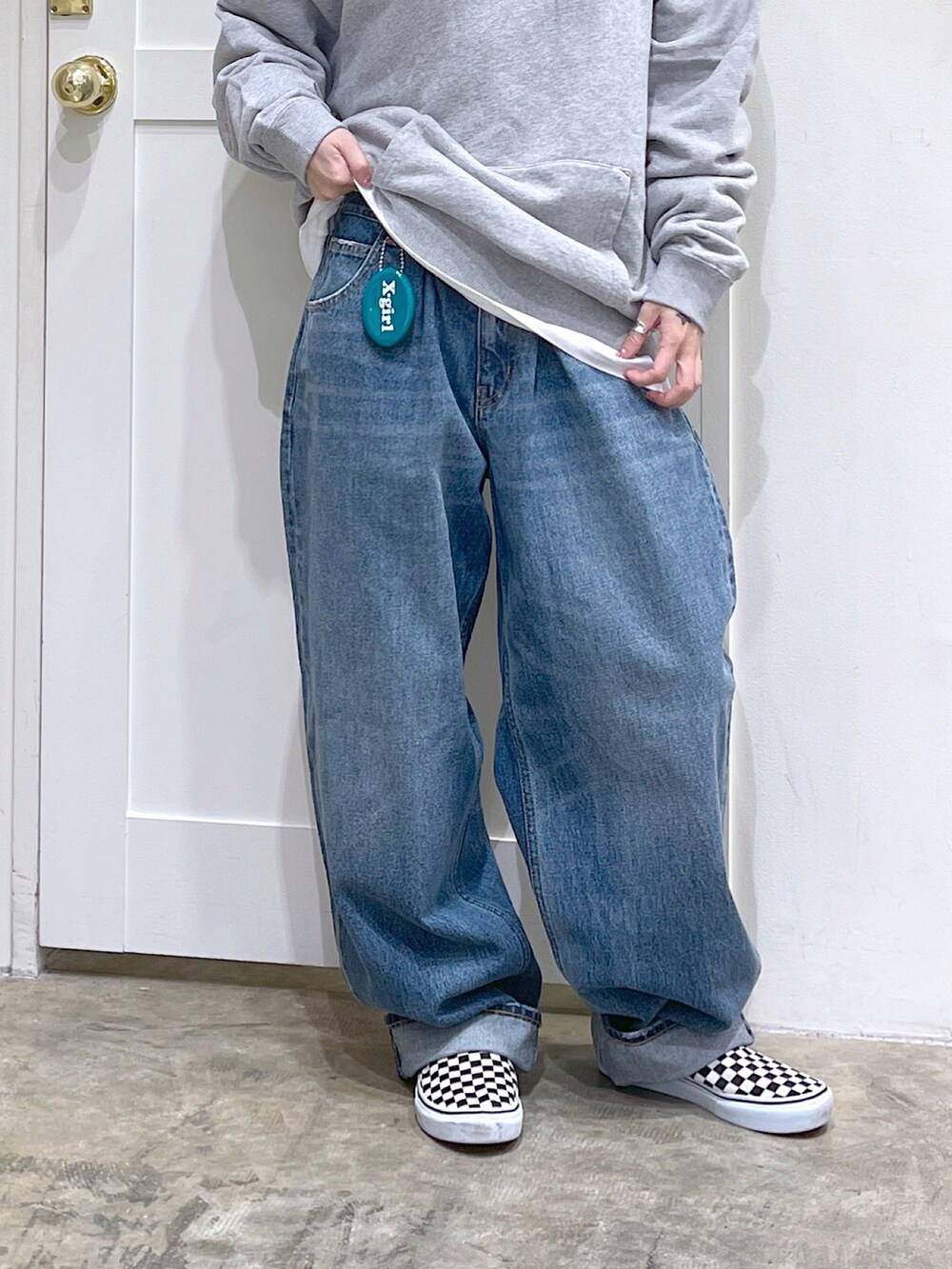 グレー系のパーカー、ブルー系のデニムパンツ、グリーン系のコインケースを着用したレディースの夏コーディネートの3枚目の写真