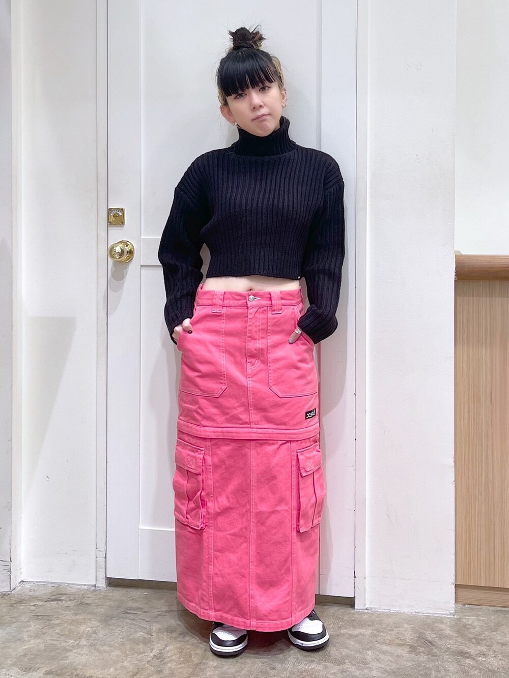 ブラック系のニット/セーター、シルバー系のショルダーバッグ、ピンク系のスカートを着用したレディースの秋コーディネートの5枚目の写真