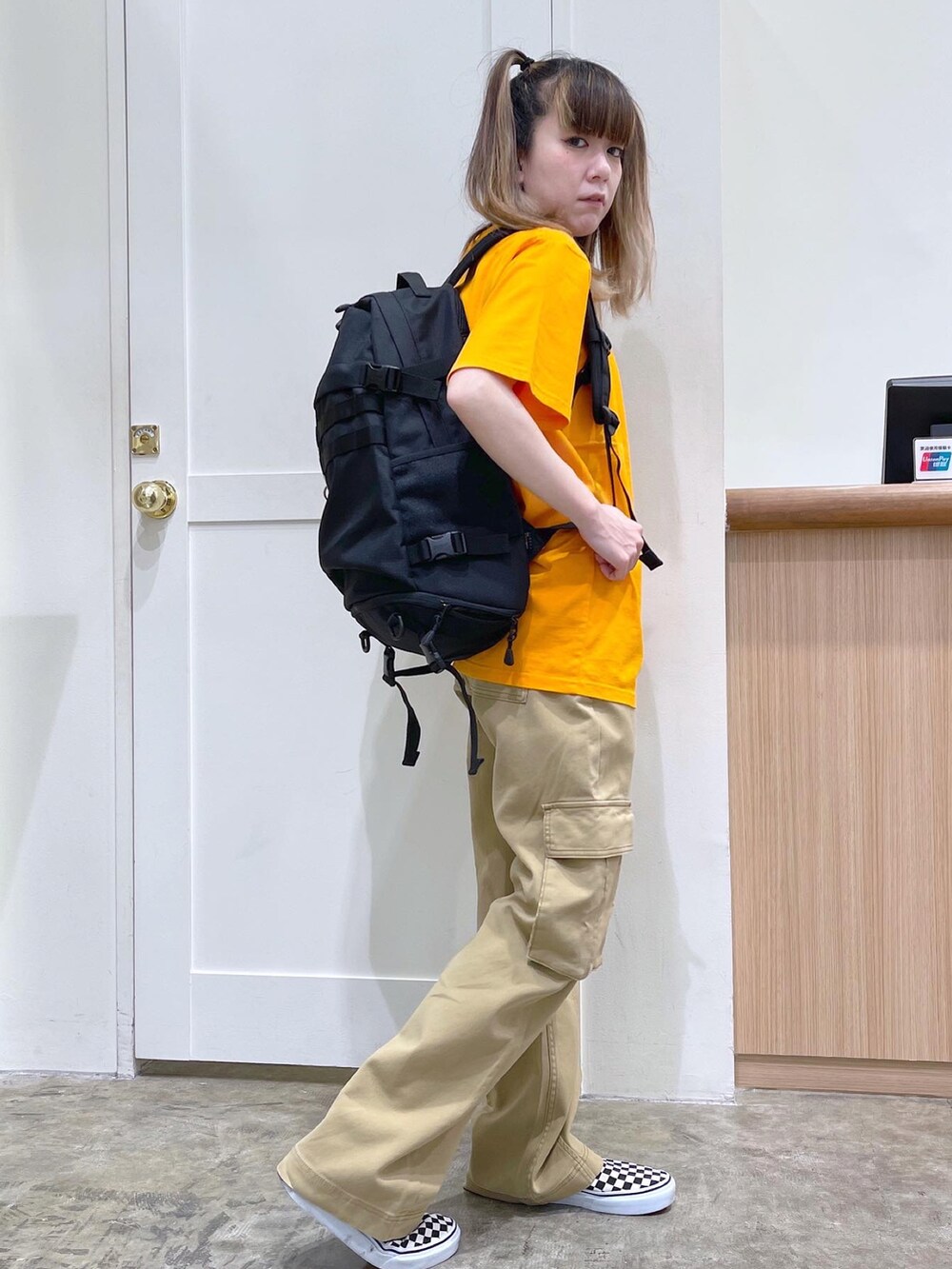 レッド系のバックパック/リュック、オレンジ系のTシャツ/カットソー、ベージュ系のカーゴパンツを着用したレディースの夏コーディネートの4枚目の写真