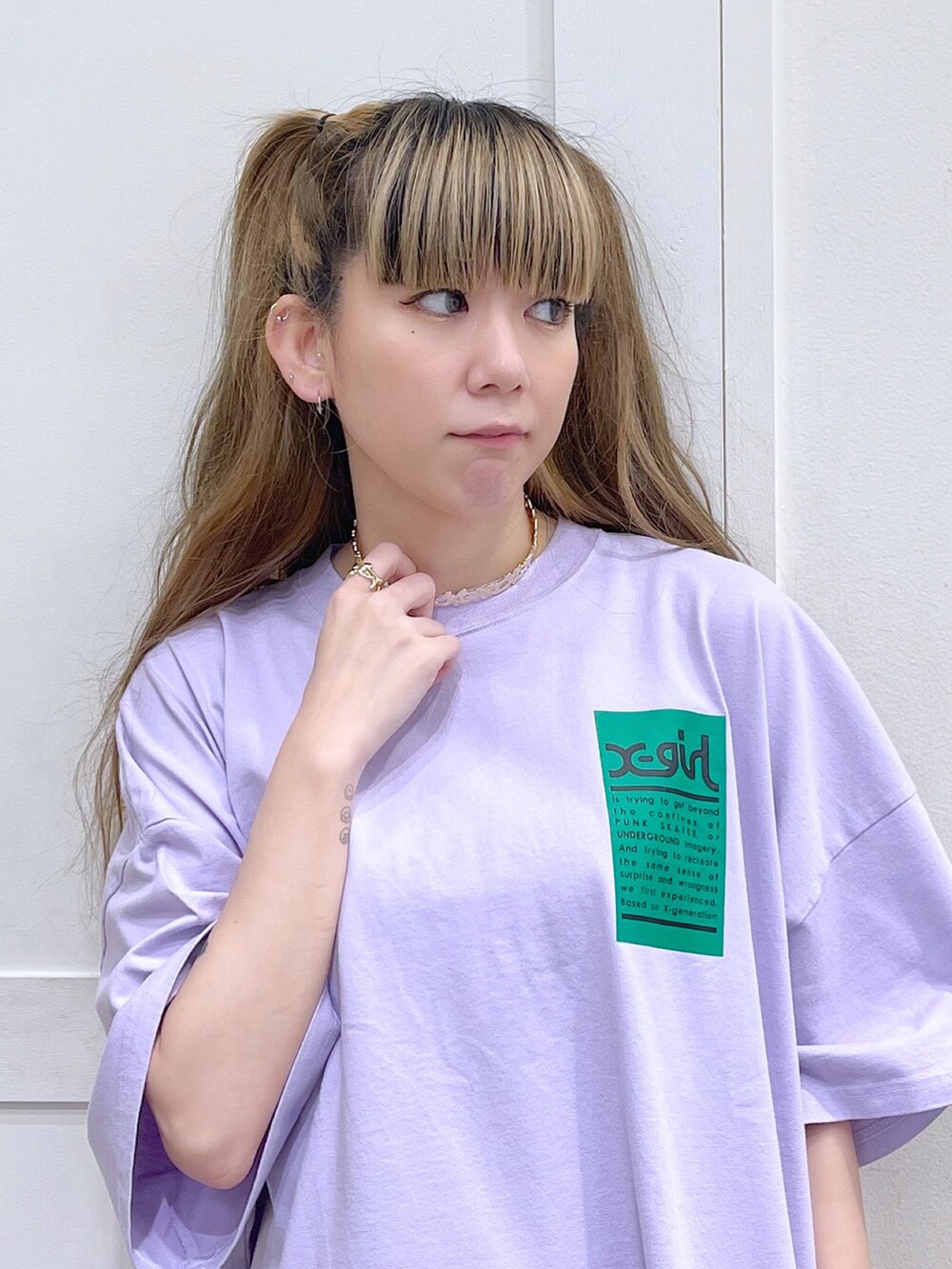 パープル系のワンピース、ブラック系のデニムパンツ、ゴールド系のチョーカーを着用したレディースの春コーディネートの5枚目の写真