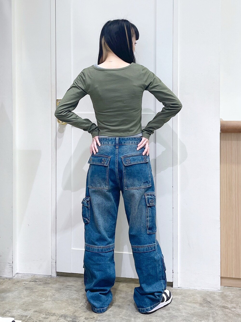 グリーン系のトップス、ブラック系のショルダーバッグ、ブルー系のデニムパンツを着用したレディースの夏コーディネートの3枚目の写真