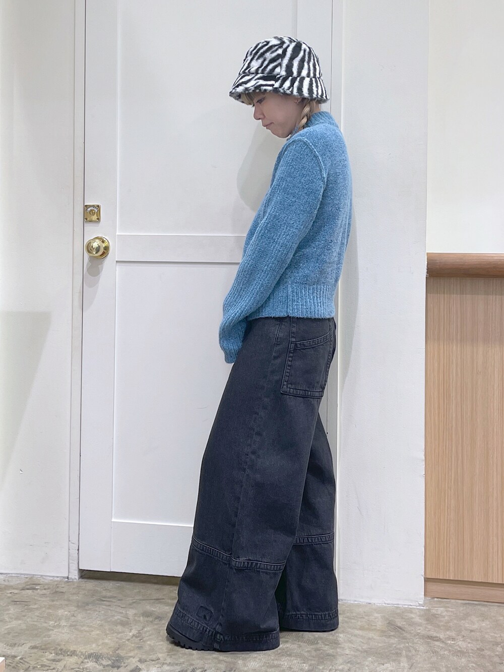 ブルー系のニット/セーター、ブラック系のデニムパンツ、ホワイト系のハットを着用したレディースの秋コーディネートの3枚目の写真