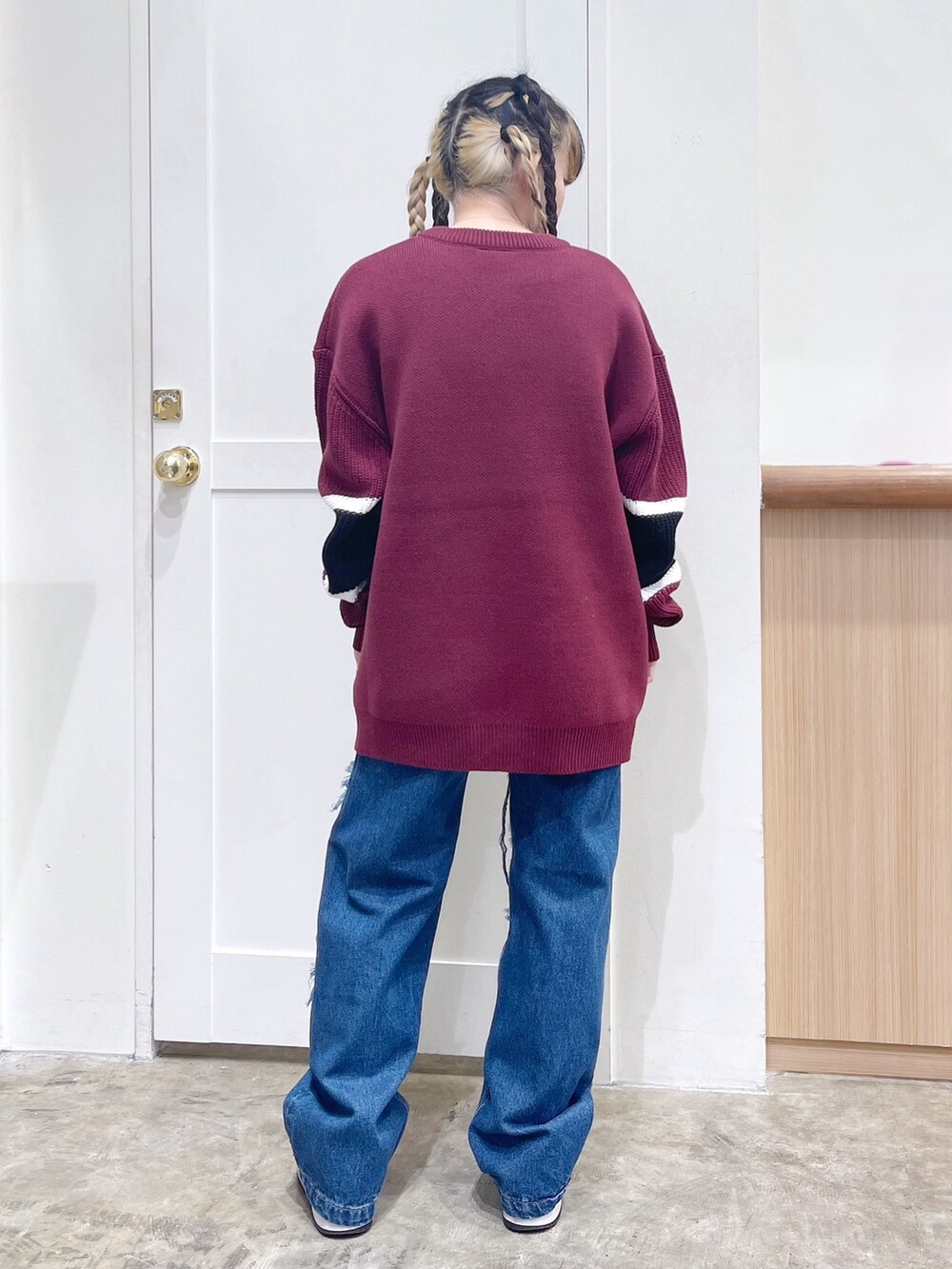 レッド系のニット/セーター、ブルー系のデニムパンツ、ホワイト系のマフラーを着用したレディースの冬コーディネートの4枚目の写真