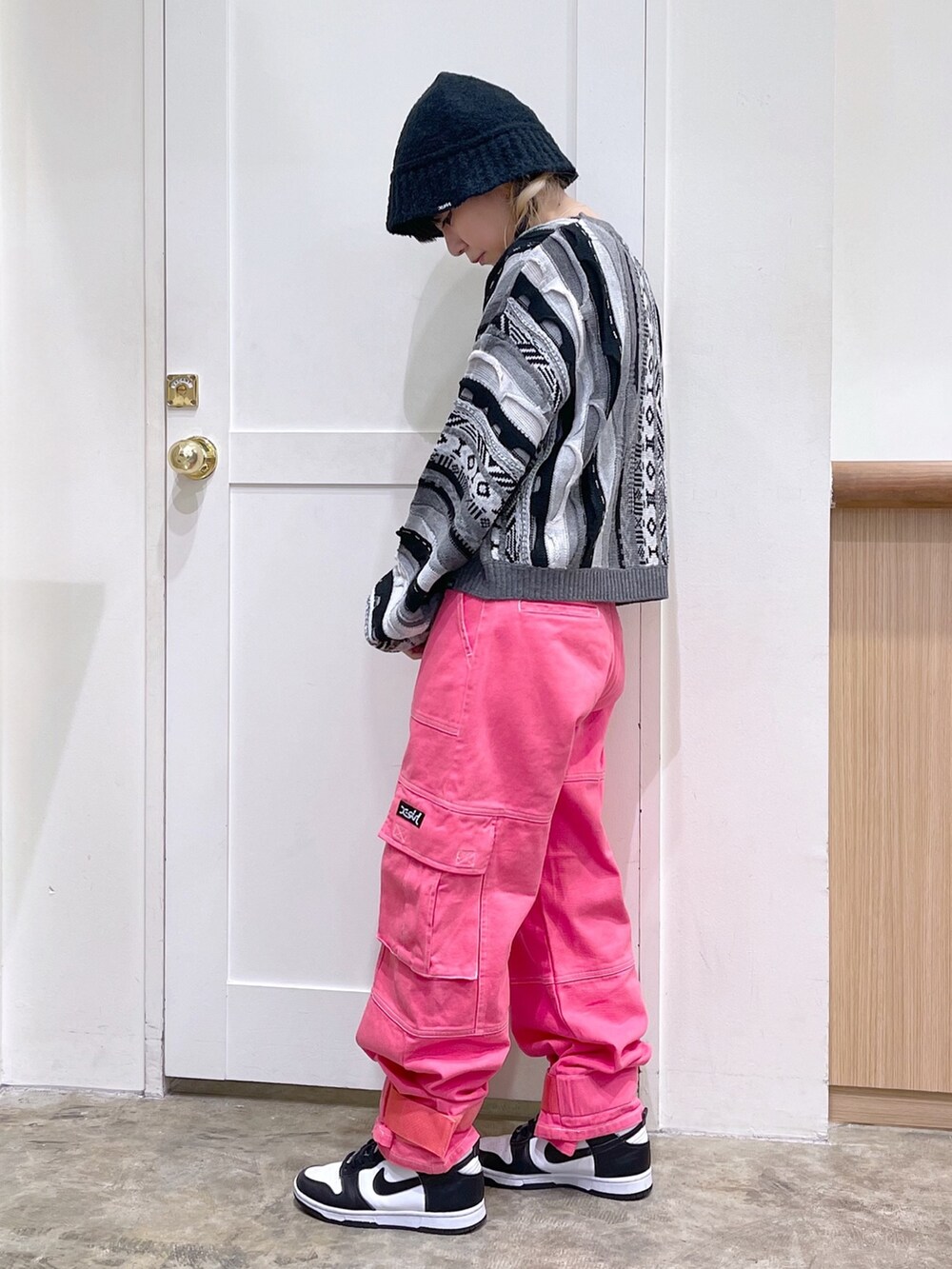 ブラック系のニット/セーター、ブラック系のメッセンジャーバッグ、ピンク系のカーゴパンツを着用したレディースの秋コーディネートの3枚目の写真