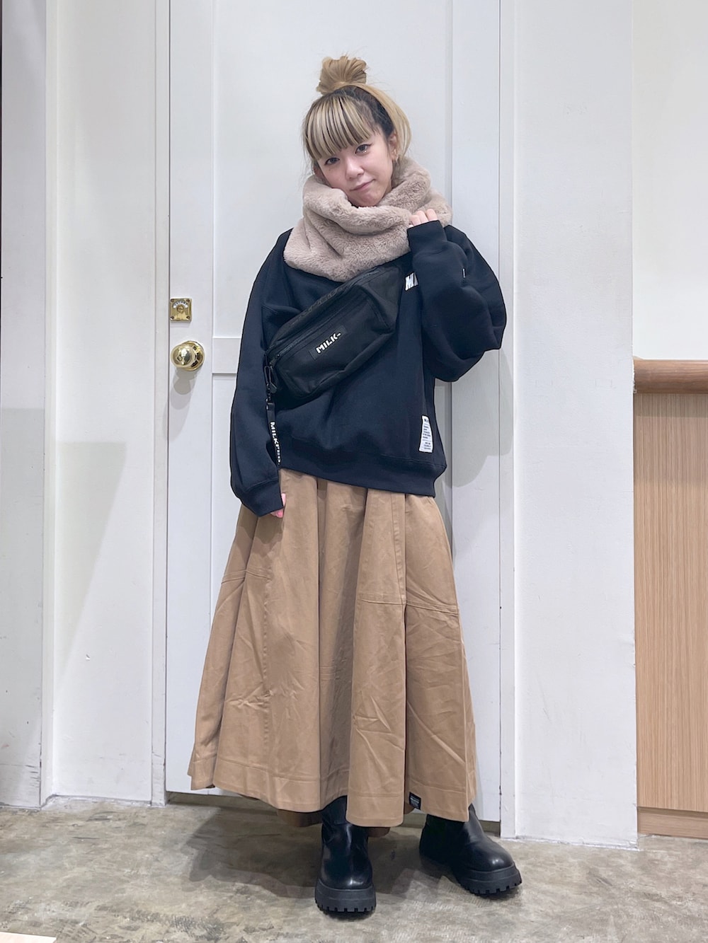 ブラック系のスウェット、ベージュ系のスカート、ブラック系のボディバッグ/ウエストポーチを着用したレディースの秋コーディネートの2枚目の写真