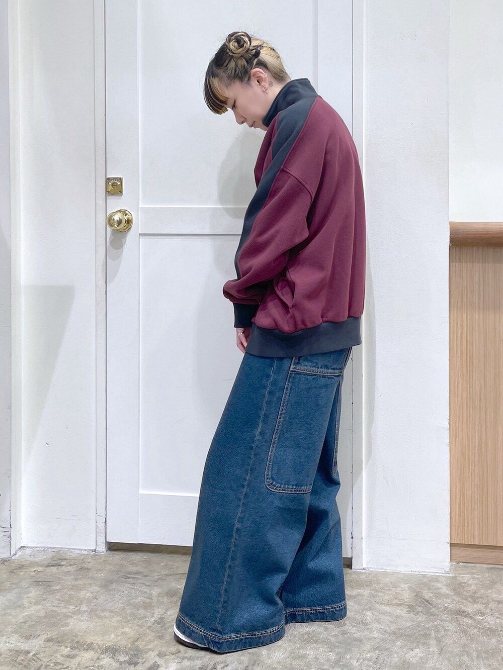 レッド系のスウェット、ブルー系のボストンバッグ、ブルー系のデニムパンツを着用したレディースの冬コーディネートの3枚目の写真