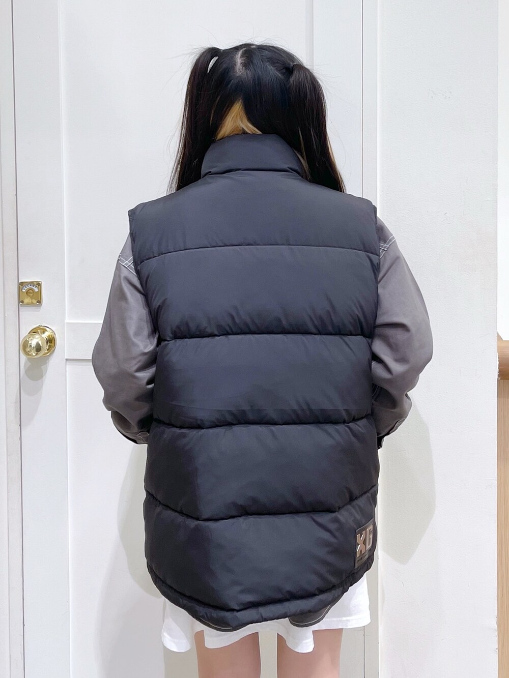 ブラック系のダウンベスト、グリーン系のシャツ/ブラウス、ホワイト系のワンピースを着用したレディースの秋コーディネートの3枚目の写真