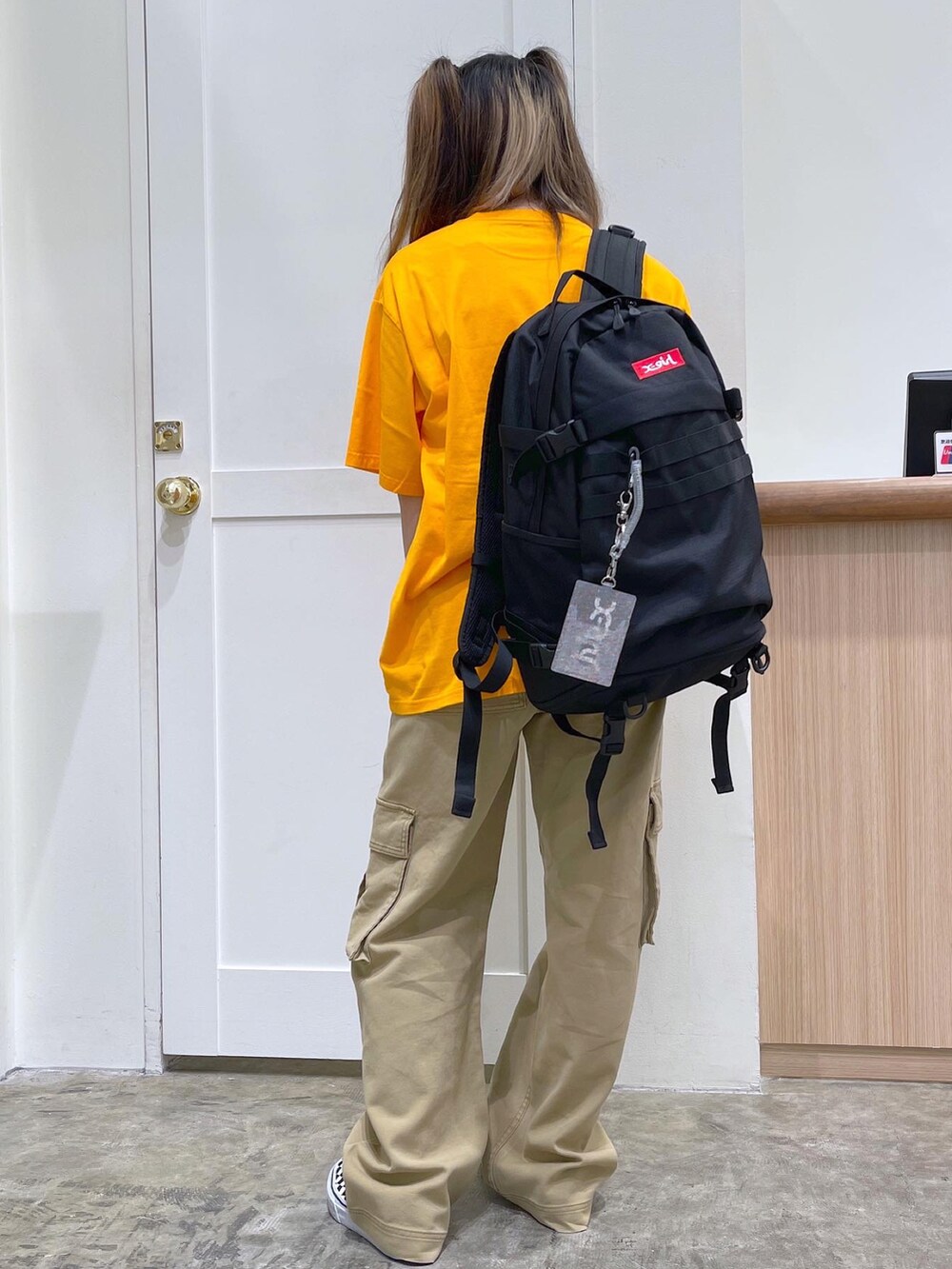 レッド系のバックパック/リュック、オレンジ系のTシャツ/カットソー、ベージュ系のカーゴパンツを着用したレディースの夏コーディネートの3枚目の写真