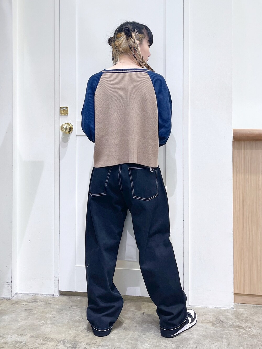 ブルー系のニット/セーター、ブラック系のデニムパンツ、ホワイト系のトートバッグを着用したレディースの秋コーディネートの4枚目の写真