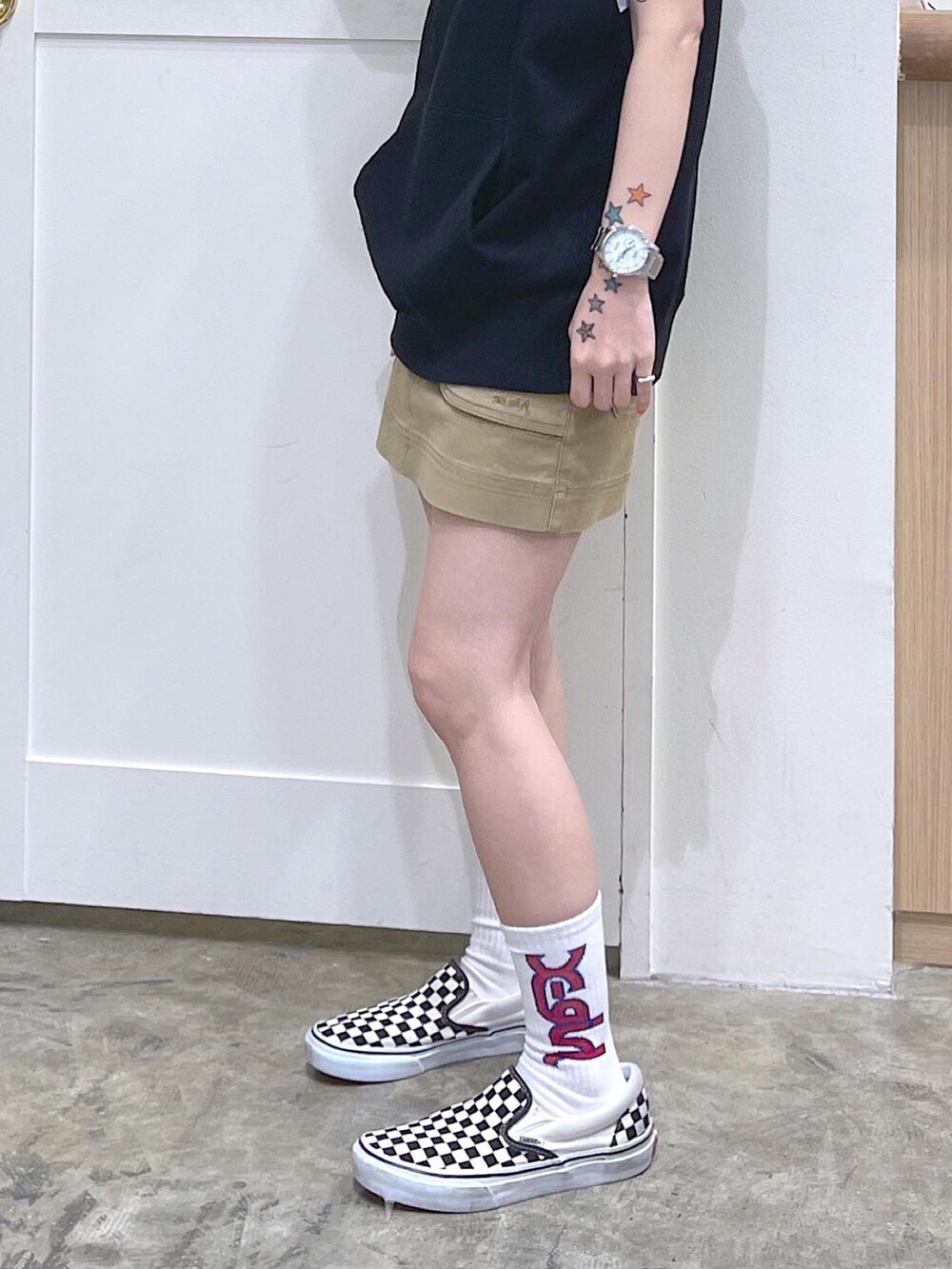 ブラック系のベスト、ホワイト系のTシャツ/カットソー、ベージュ系のスカートを着用したレディースの夏コーディネートの3枚目の写真