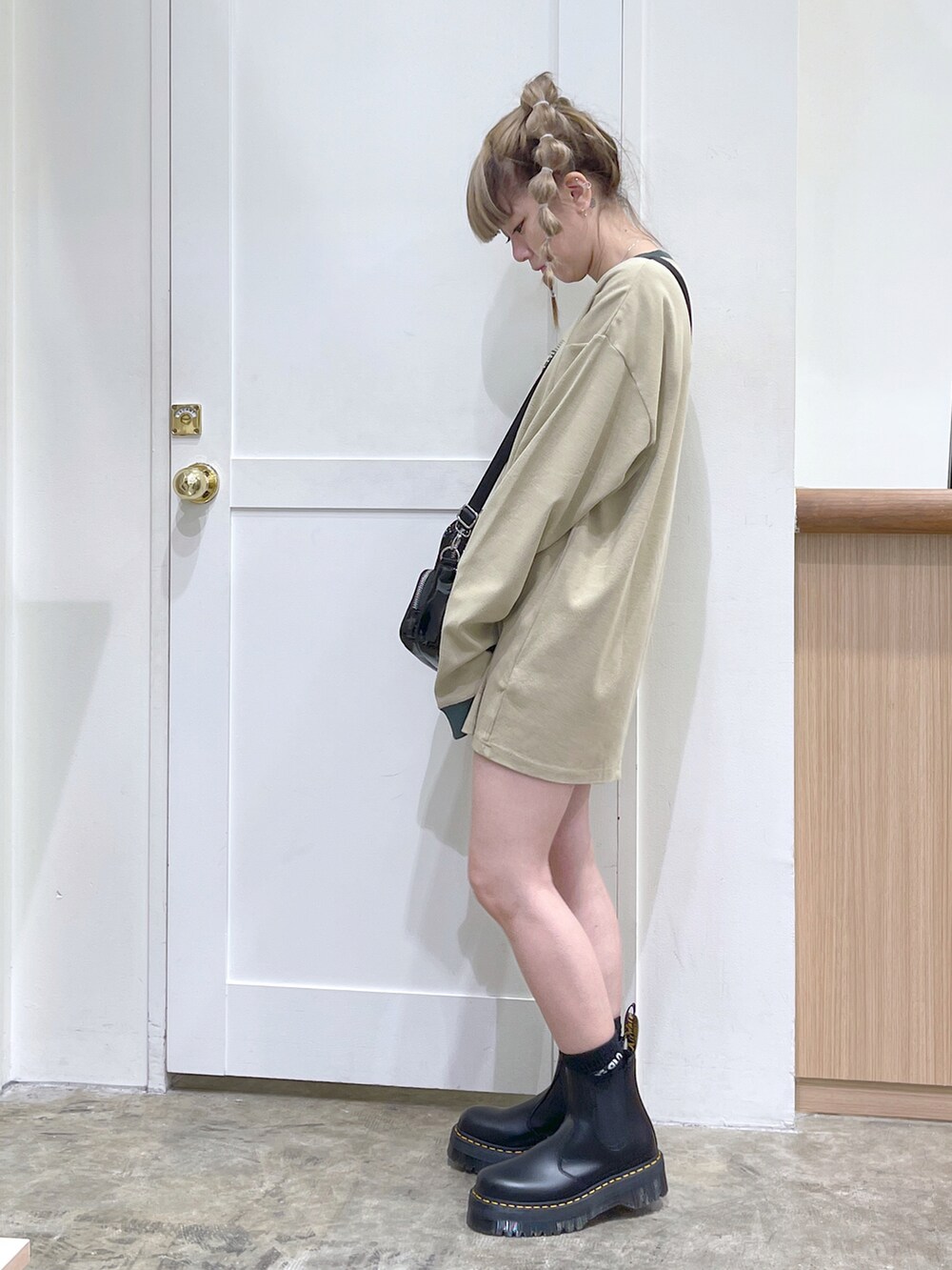 ベージュ系のTシャツ/カットソー、ブラック系のショルダーバッグ、ブラック系のブーツを着用したレディースの夏コーディネートの2枚目の写真