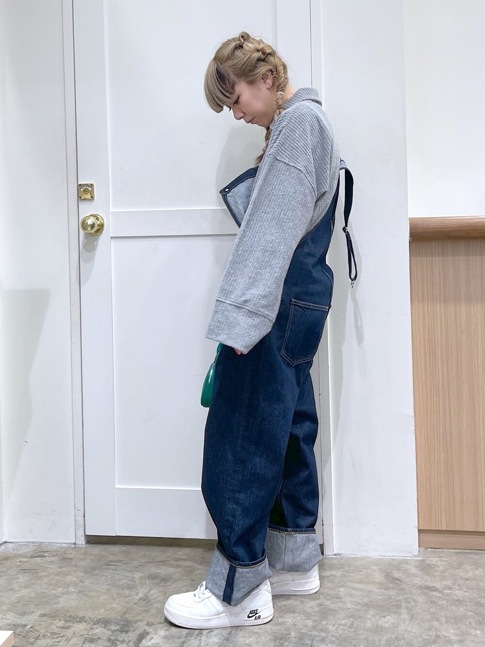 グレー系のスウェット、ブルー系のサロペット/オーバーオール、グリーン系のショルダーバッグを着用したレディースの冬コーディネートの4枚目の写真