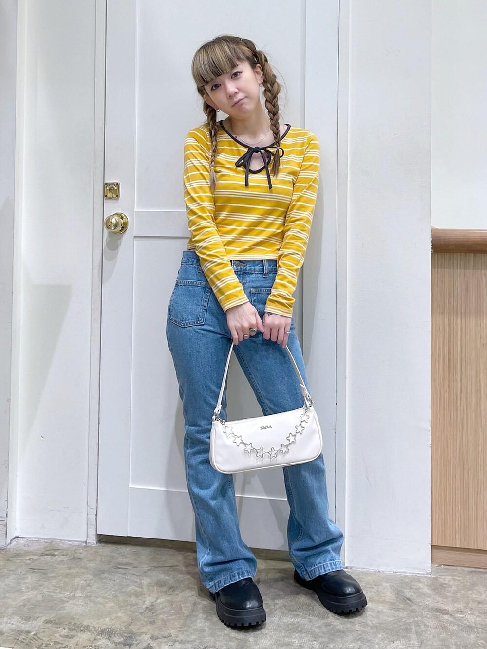 イエロー系のTシャツ/カットソー、ホワイト系のハンドバッグ、ブルー系のデニムパンツを着用したレディースの春コーディネートの2枚目の写真