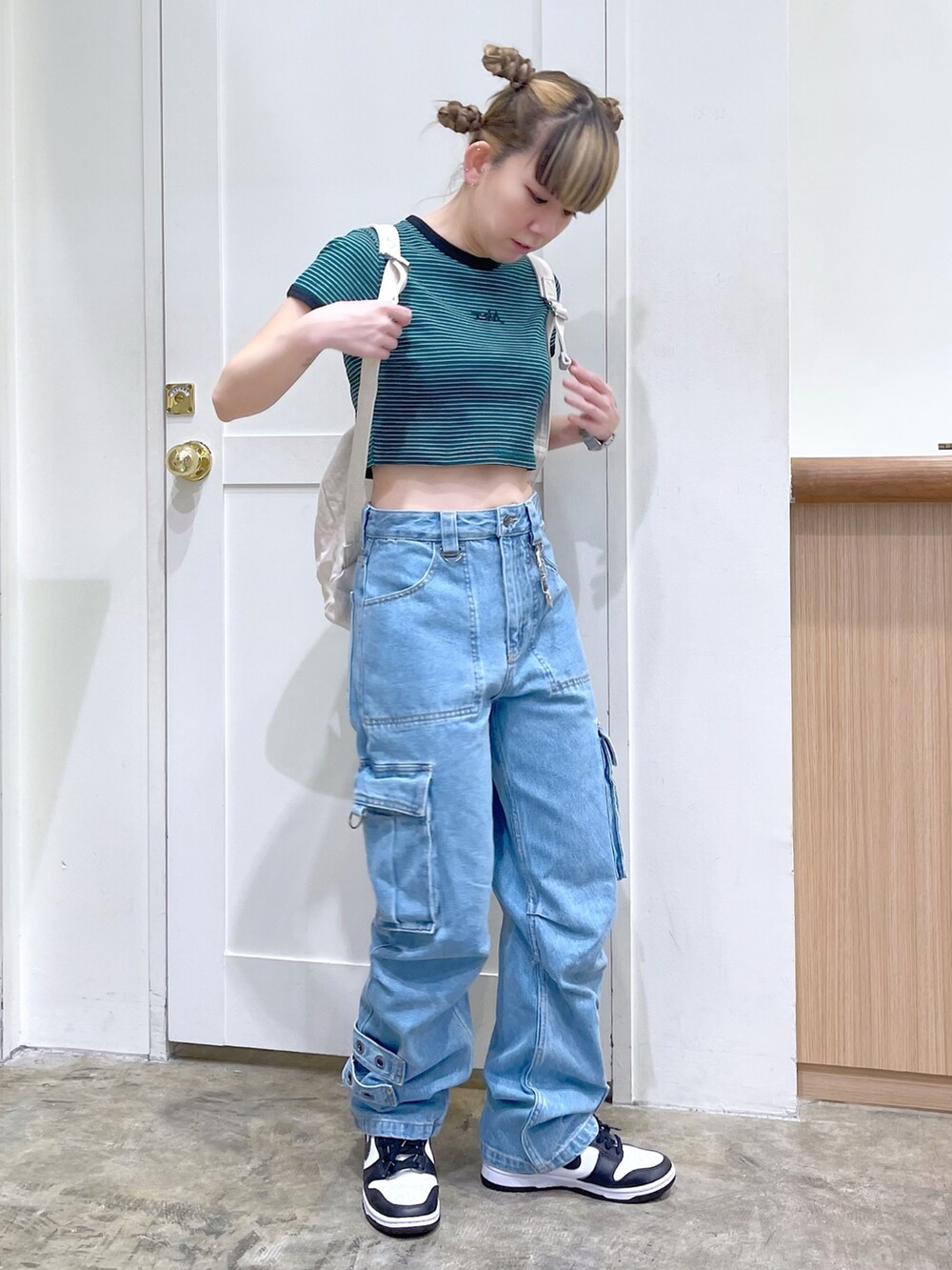 グリーン系のTシャツ/カットソー、ブルー系のカーゴパンツ、ホワイト系のバックパック/リュックを着用したレディースの春コーディネートの2枚目の写真