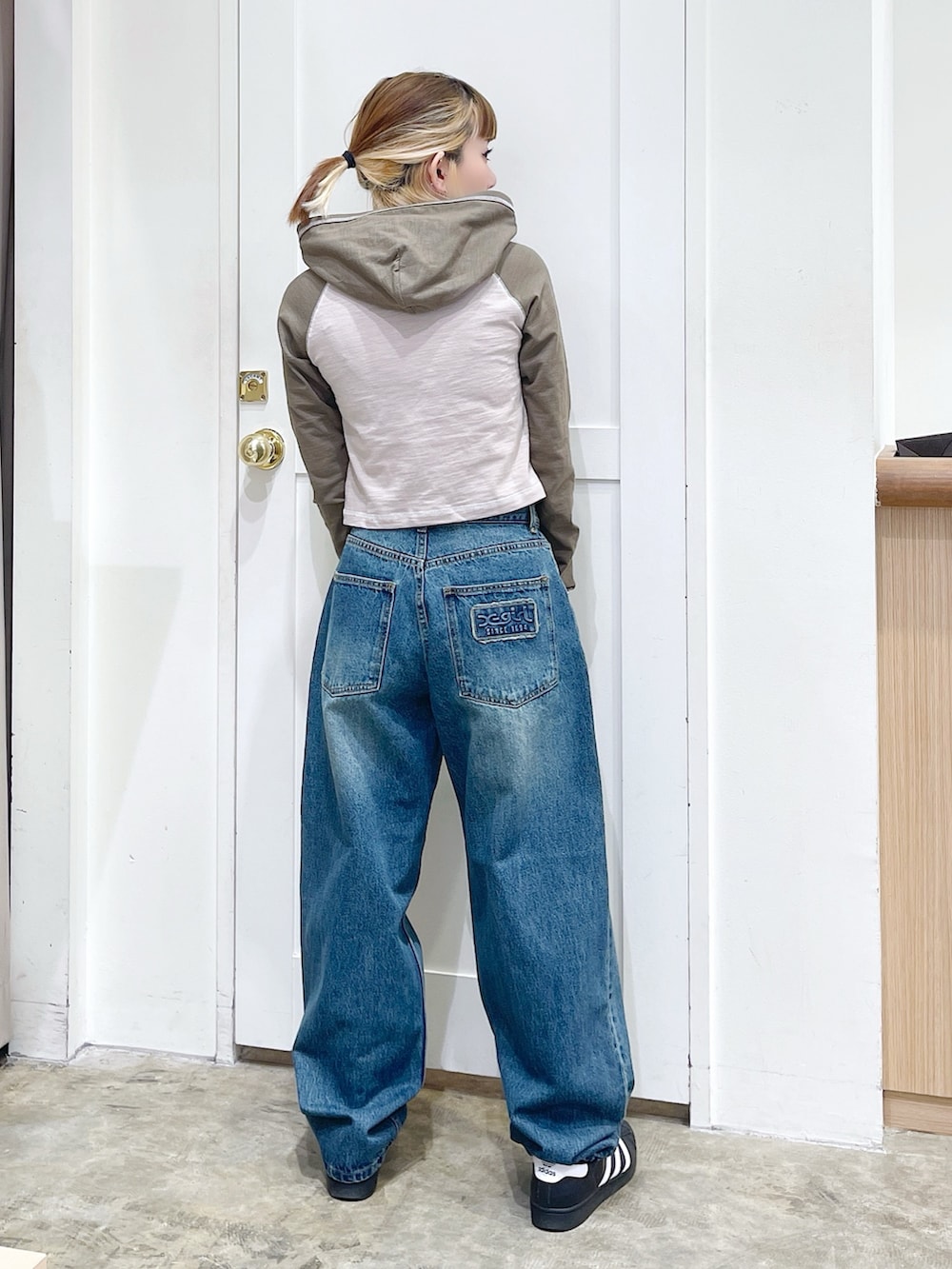 ベージュ系のパーカー、ブルー系のデニムパンツ、ブラック系のショルダーバッグを着用したレディースの春コーディネートの4枚目の写真