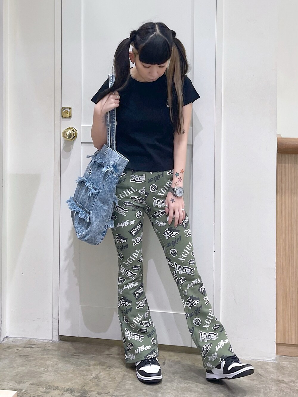 ブラック系のTシャツ/カットソー、グリーン系のその他パンツ、ブルー系のトートバッグを着用したレディースの春コーディネートの2枚目の写真