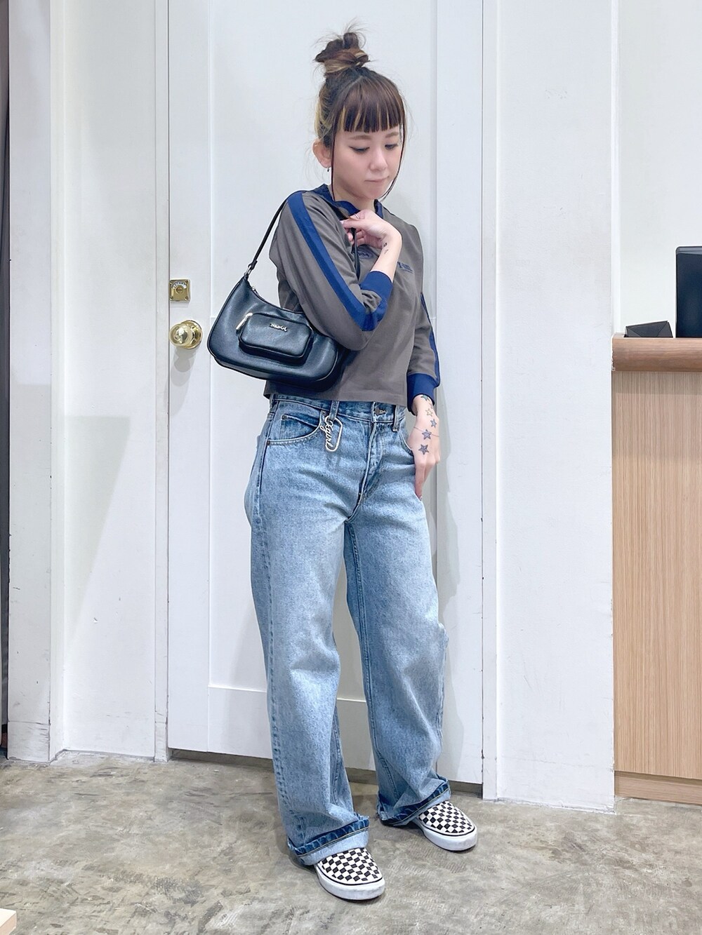 グリーン系のTシャツ/カットソー、ブルー系のデニムパンツ、シルバー系のハンドバッグを着用したレディースの秋コーディネートの2枚目の写真