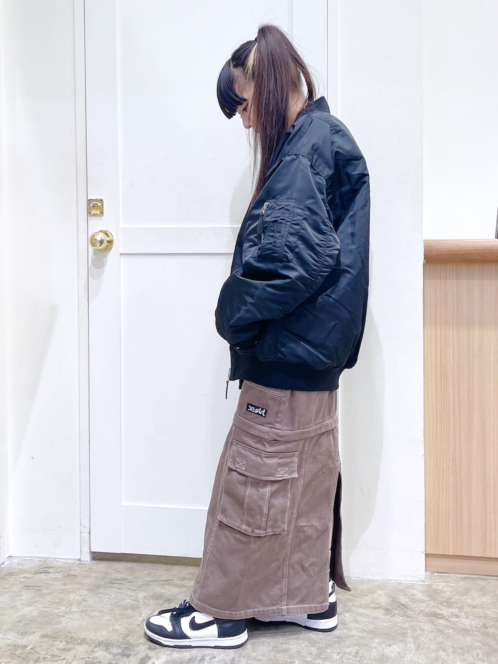 ブラック系のMA-1、ホワイト系のTシャツ/カットソー、グリーン系のスカートを着用したレディースの秋コーディネートの3枚目の写真