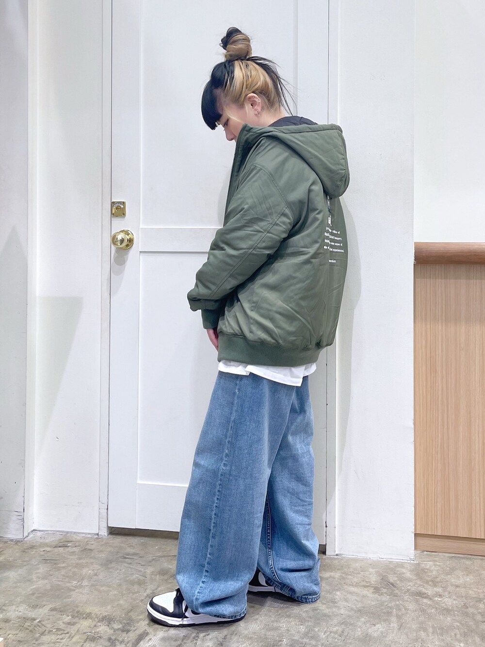 グリーン系のナイロンジャケット、ブラック系のスウェット、ブルー系のデニムパンツを着用したレディースの秋コーディネートの3枚目の写真