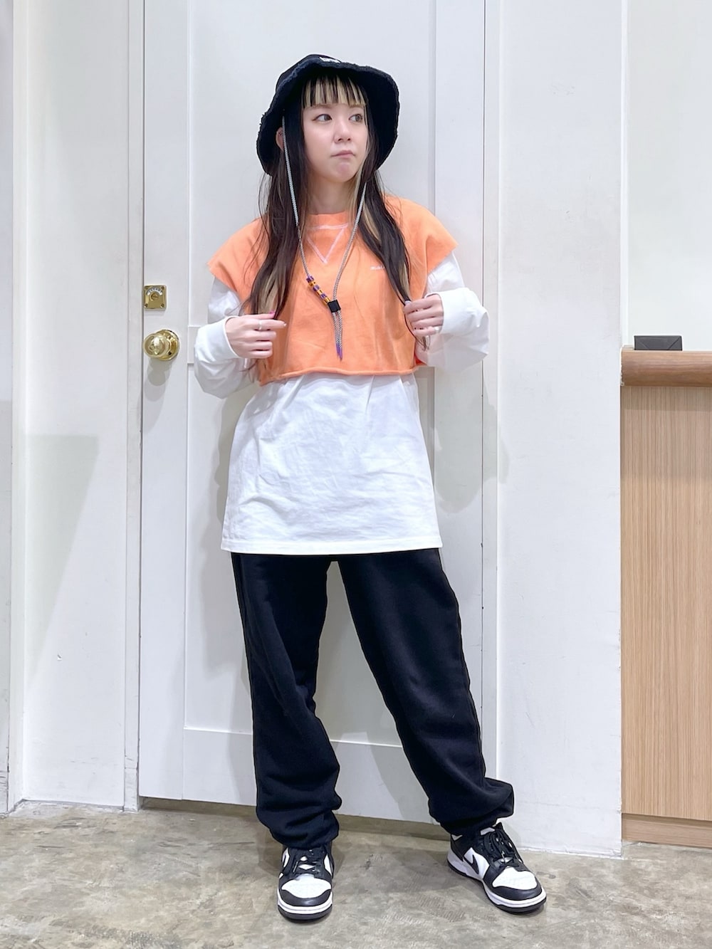 オレンジ系のベスト、ホワイト系のTシャツ/カットソー、ブラック系のスウェットパンツを着用したレディースの春コーディネートの2枚目の写真