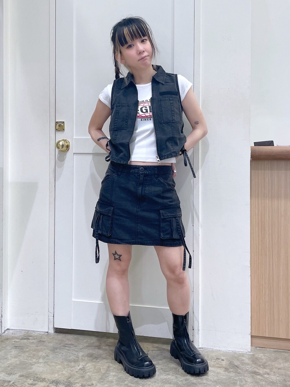 ブラック系のベスト、ブラック系のスカート、ホワイト系のTシャツ/カットソーを着用したレディースの春コーディネートの2枚目の写真