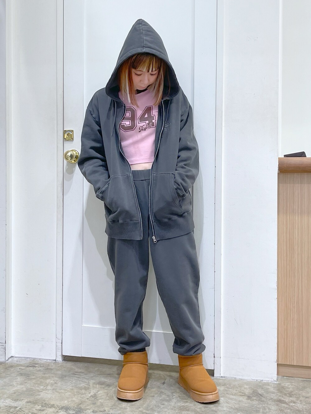 ブラック系のパーカー、ブラック系のスウェットパンツ、ピンク系のTシャツ/カットソーを着用したレディースの冬コーディネートの2枚目の写真