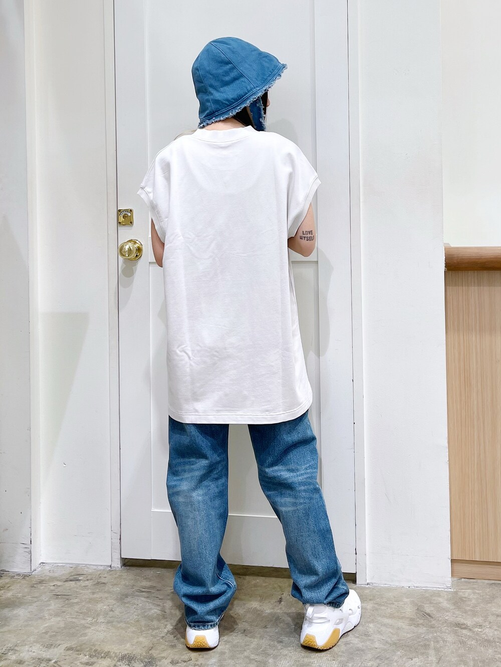 ホワイト系のワンピース、ブルー系のデニムパンツ、ホワイト系のスニーカーを着用したレディースの夏コーディネートの4枚目の写真