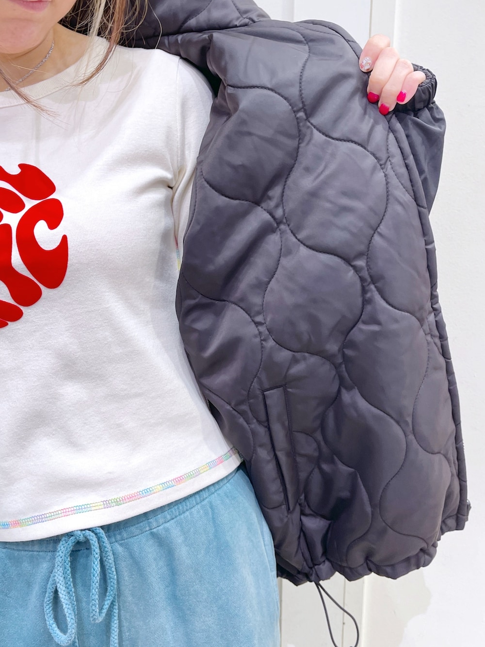 ブラック系のナイロンジャケット、ホワイト系のTシャツ/カットソー、ブルー系のスウェットパンツを着用したレディースの秋コーディネートの4枚目の写真