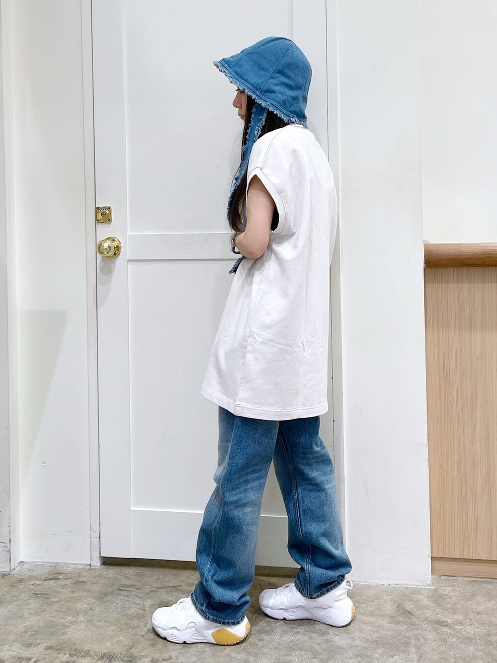 ホワイト系のワンピース、ブルー系のデニムパンツ、ホワイト系のスニーカーを着用したレディースの夏コーディネートの3枚目の写真