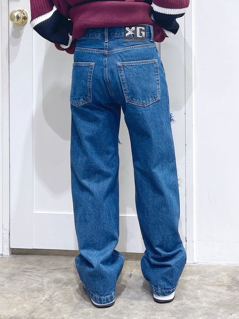 レッド系のニット/セーター、ブルー系のデニムパンツ、ホワイト系のマフラーを着用したレディースの冬コーディネートの6枚目の写真