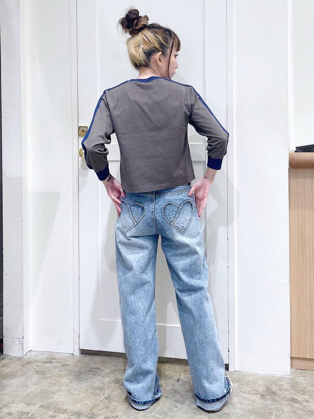 グリーン系のTシャツ/カットソー、ブルー系のデニムパンツ、シルバー系のハンドバッグを着用したレディースの秋コーディネートの4枚目の写真