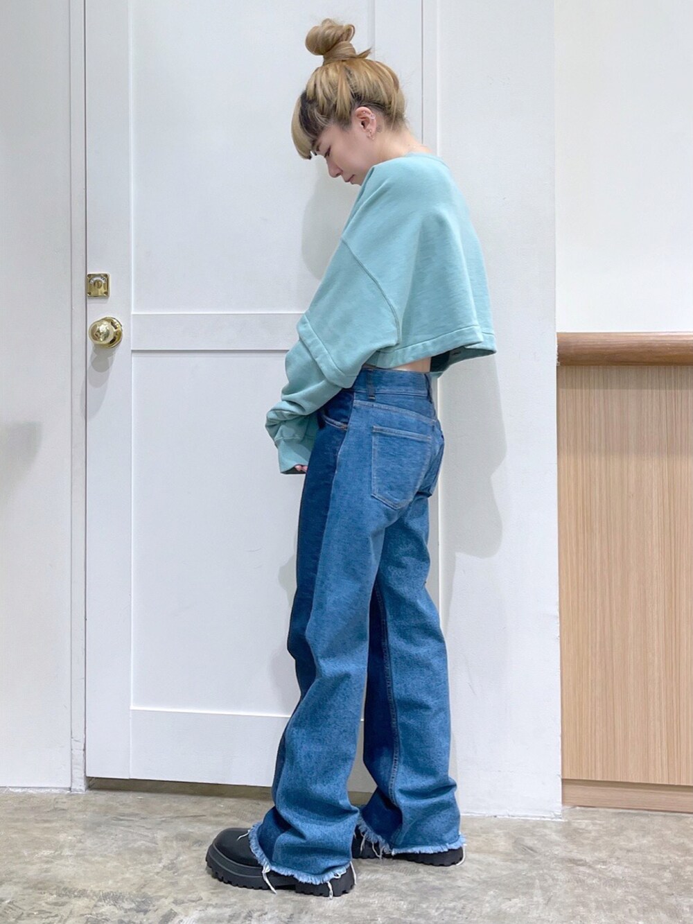 グリーン系のワンピース、ブルー系のデニムパンツ、ブラック系のショルダーバッグを着用したレディースの冬コーディネートの4枚目の写真