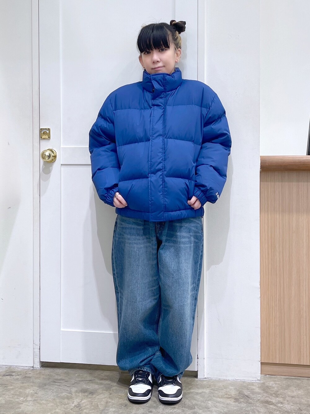 ブルー系のダウンジャケット/コート、グレー系のニット/セーター、ブルー系のデニムパンツを着用したレディースの秋コーディネートの3枚目の写真