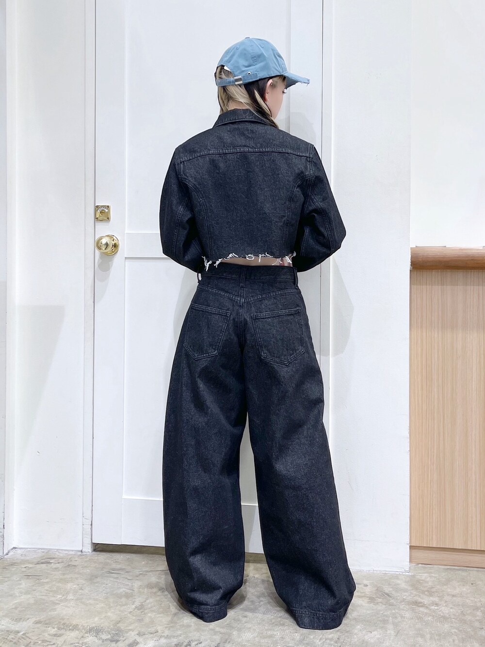 ブラック系のデニムジャケット、ブラック系のデニムパンツ、ブルー系のキャップを着用したレディースの冬コーディネートの4枚目の写真