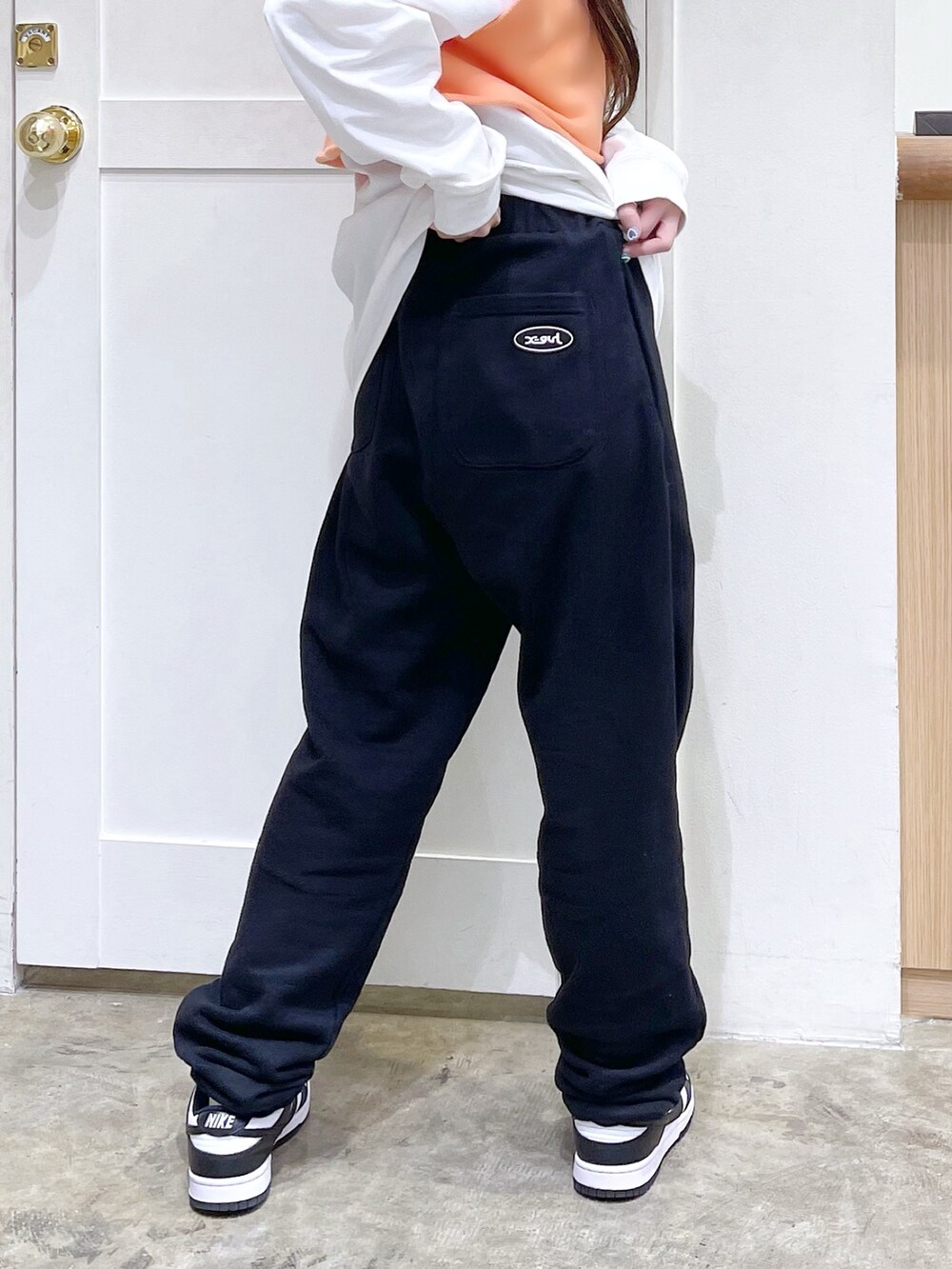 オレンジ系のベスト、ホワイト系のTシャツ/カットソー、ブラック系のスウェットパンツを着用したレディースの春コーディネートの5枚目の写真
