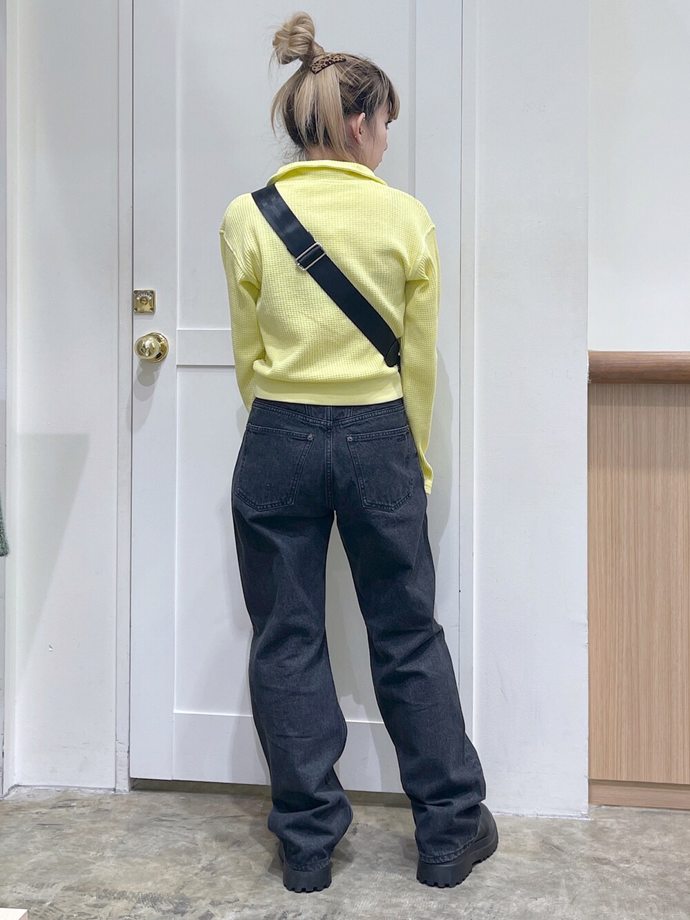 イエロー系のTシャツ/カットソー、ブラック系のショルダーバッグ、ブラック系のデニムパンツを着用したレディースの秋コーディネートの3枚目の写真