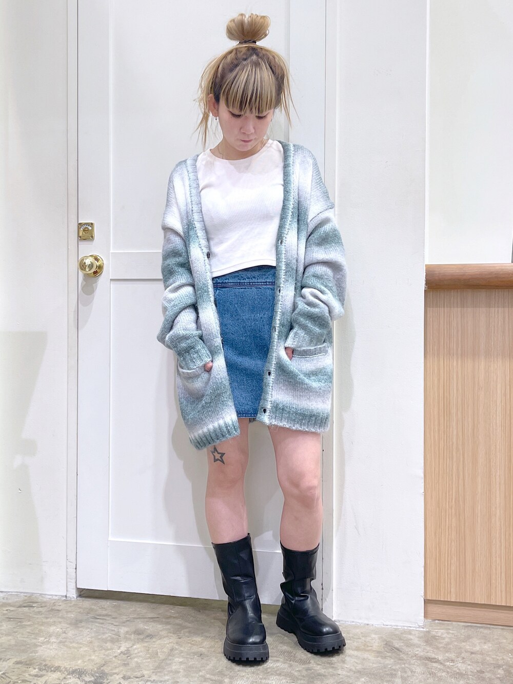 グレー系のカーディガン/ボレロ、ホワイト系のTシャツ/カットソー、ブルー系のデニムスカートを着用したレディースの秋コーディネートの4枚目の写真