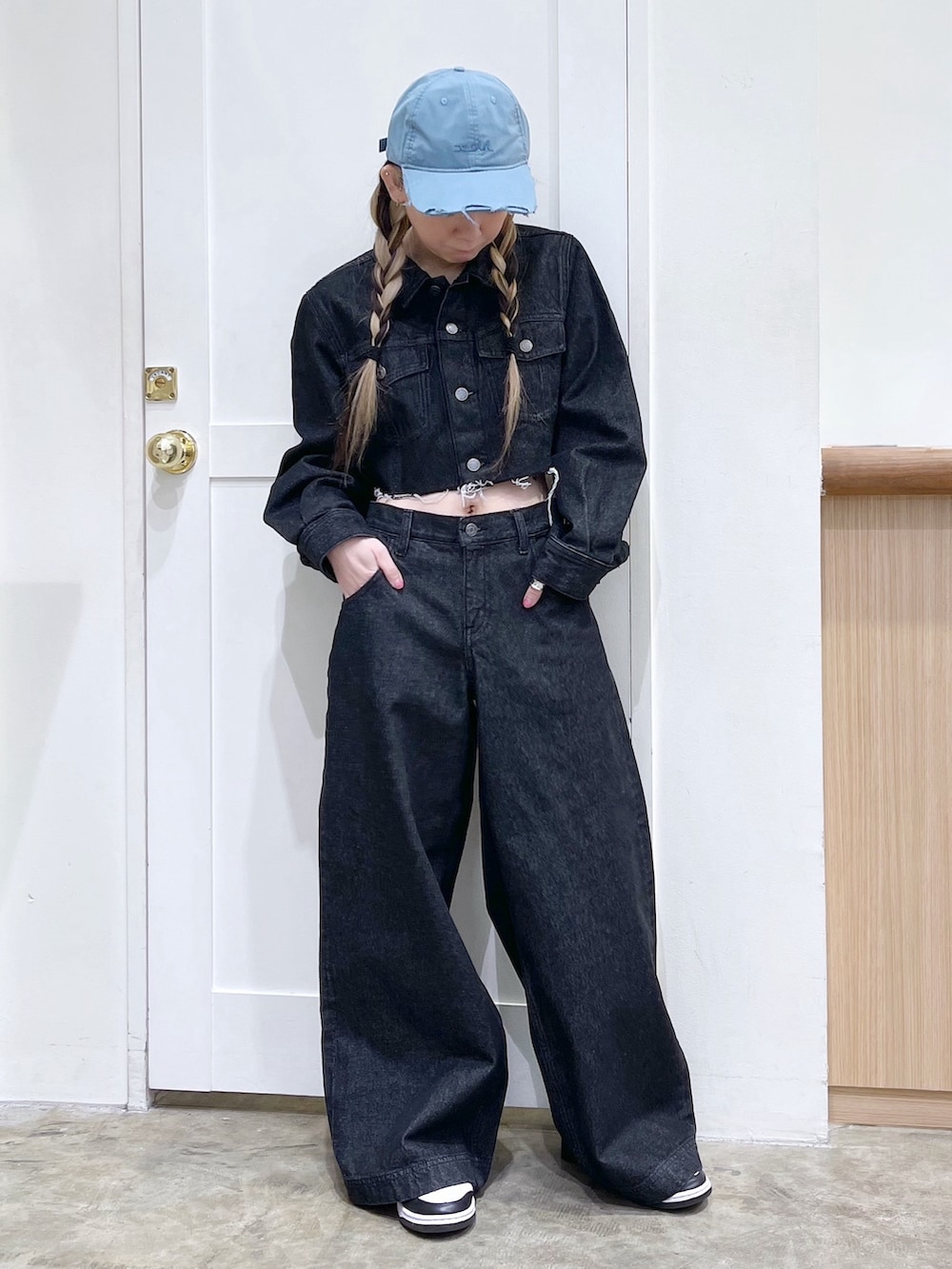 ブラック系のデニムジャケット、ブラック系のデニムパンツ、ブルー系のキャップを着用したレディースの冬コーディネートの2枚目の写真