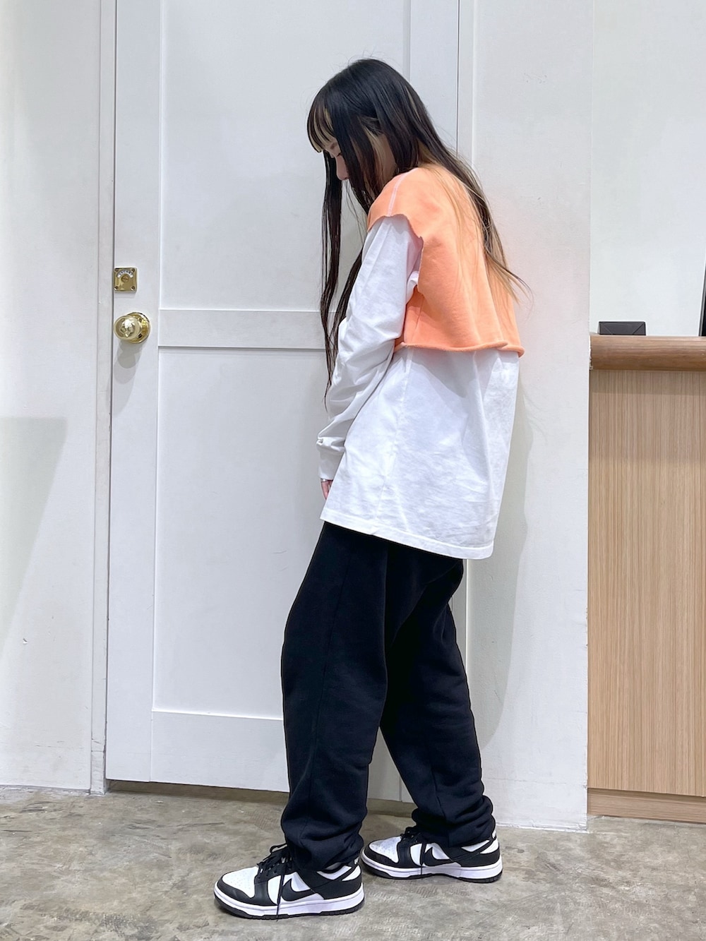 オレンジ系のベスト、ホワイト系のTシャツ/カットソー、ブラック系のスウェットパンツを着用したレディースの春コーディネートの3枚目の写真