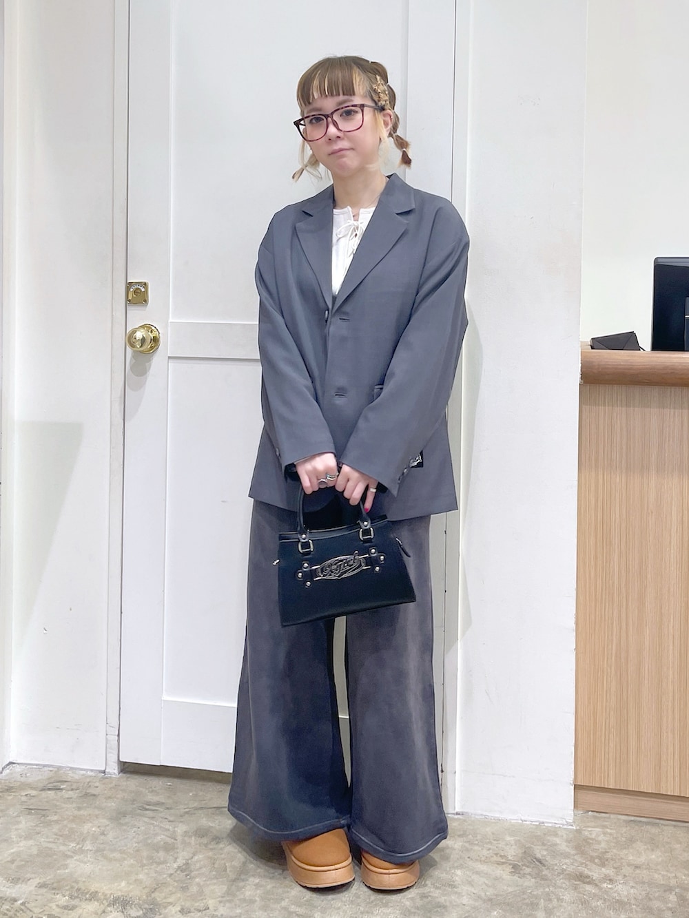 グレー系のテーラードジャケット、ブラック系のスウェットパンツ、ブラック系のショルダーバッグを着用したレディースの冬コーディネートの2枚目の写真