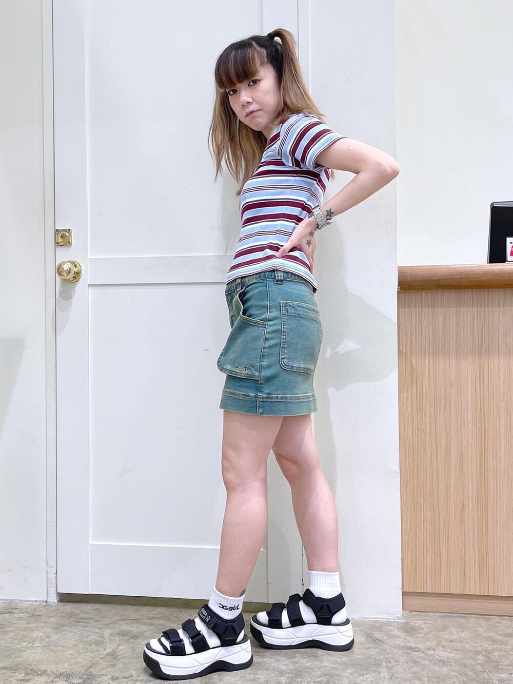 レッド系のTシャツ/カットソー、ブルー系のスカート、ブラック系のサンダルを着用したレディースの夏コーディネートの2枚目の写真