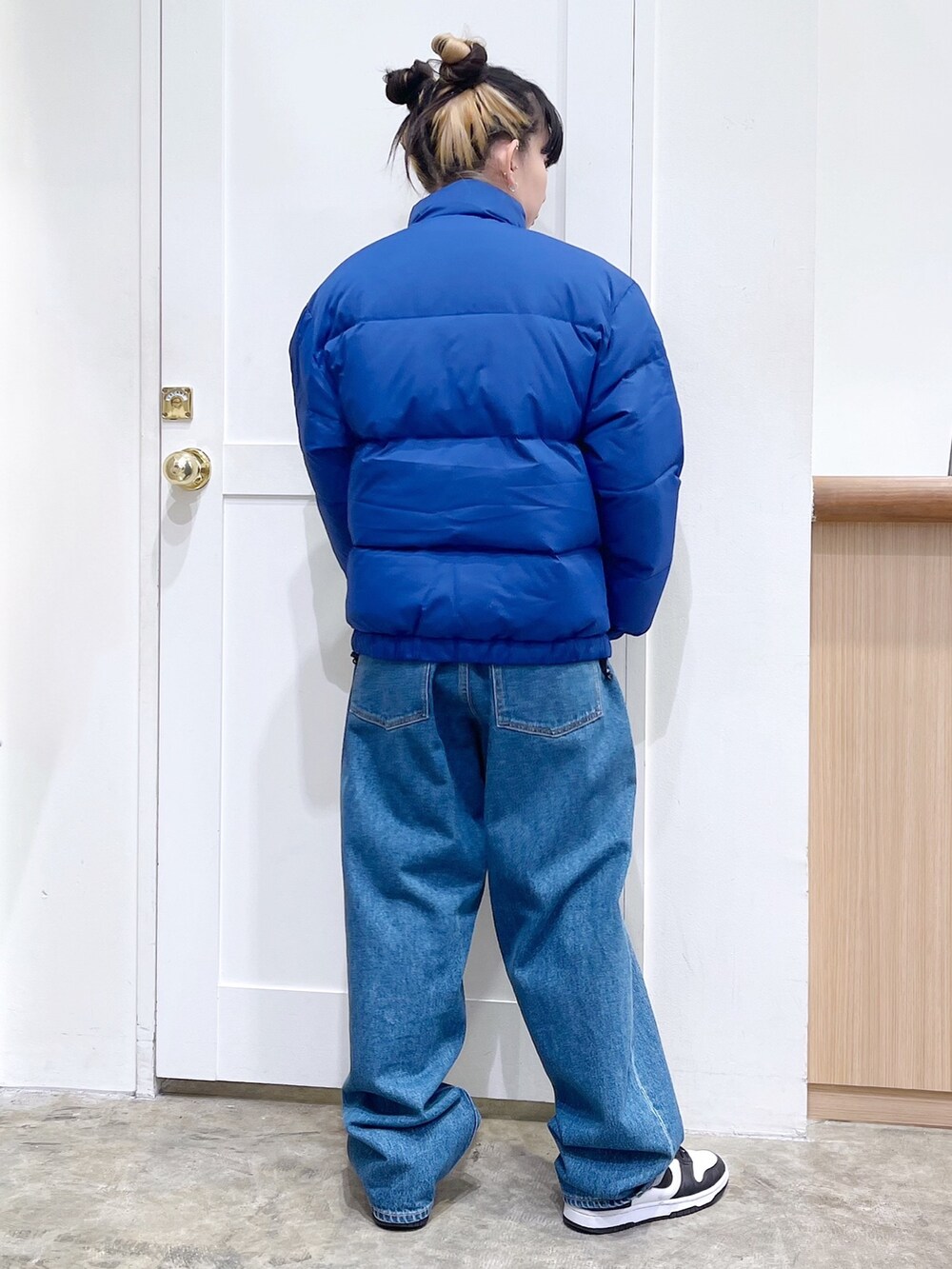 ブルー系のダウンジャケット/コート、グレー系のニット/セーター、ブルー系のデニムパンツを着用したレディースの秋コーディネートの5枚目の写真