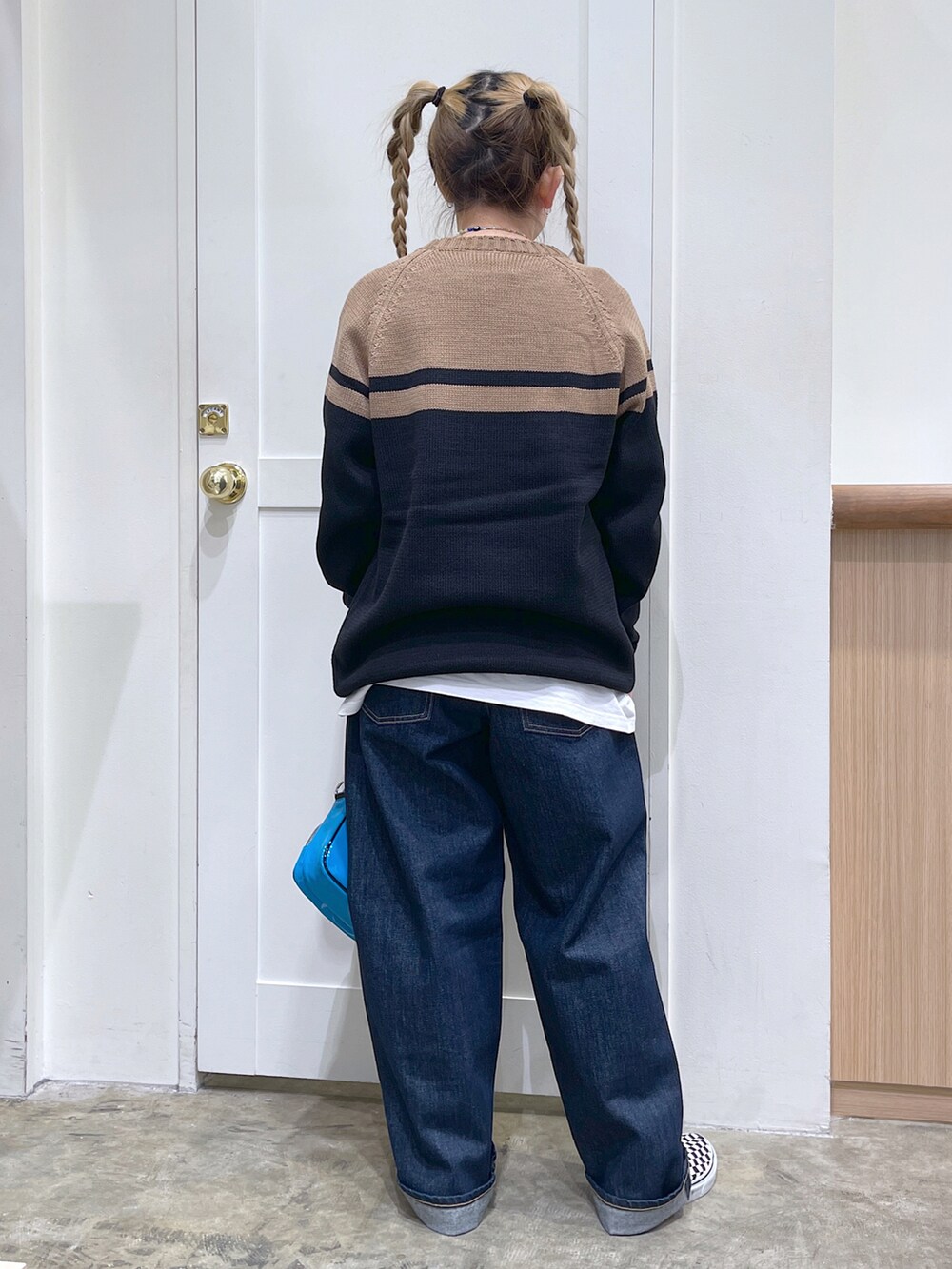 ブラック系のワンピース、ブルー系のデニムパンツ、ブルー系のショルダーバッグを着用したレディースの秋コーディネートの4枚目の写真