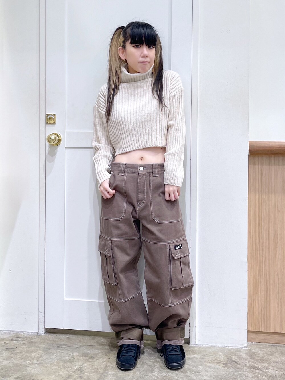 ベージュ系のパーカー、ホワイト系のニット/セーター、グリーン系のカーゴパンツを着用したレディースの秋コーディネートの4枚目の写真