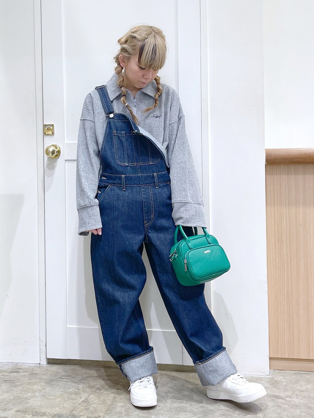 グレー系のスウェット、ブルー系のサロペット/オーバーオール、グリーン系のショルダーバッグを着用したレディースの冬コーディネートの2枚目の写真