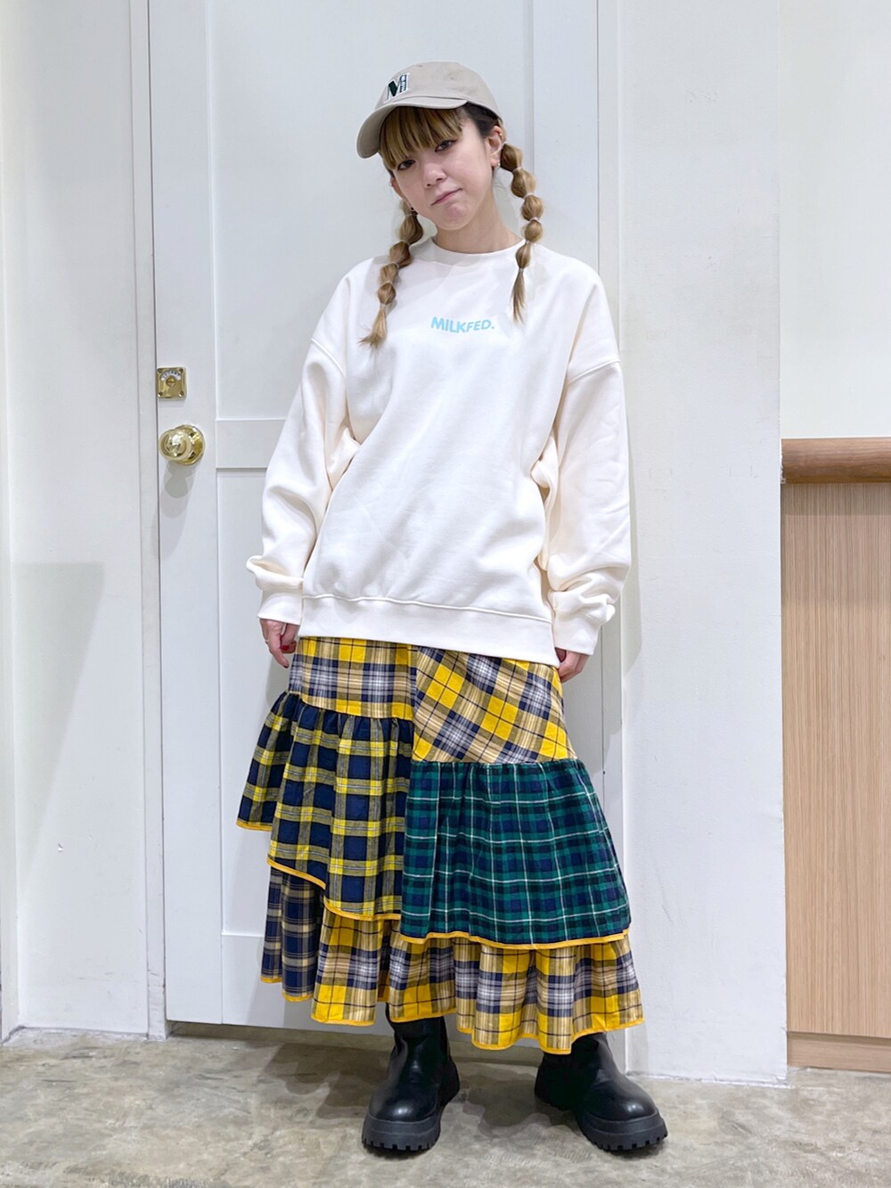 ホワイト系のスウェット、イエロー系のスカート、ベージュ系のキャップを着用したレディースの秋コーディネートの3枚目の写真